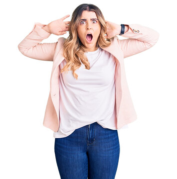 Young caucasian woman wearing business clothes crazy and scared with hands on head, afraid and surprised of shock with open mouth