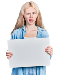 Young caucasian woman holding blank empty banner winking looking at the camera with sexy...