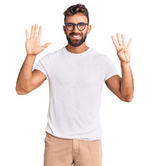 Young hispanic man wearing casual clothes and glasses showing and pointing up with fingers number nine while smiling confident and happy.