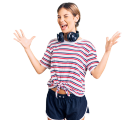 Beautiful caucasian woman with blonde hair wearing gym clothes and using headphones crazy and mad shouting and yelling with aggressive expression and arms raised. frustration concept.
