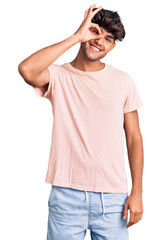 Fototapeta premium Young hispanic man wearing casual clothes smiling happy doing ok sign with hand on eye looking through fingers