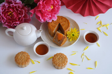 Top view of Chinese Mid-Autumn Festival concept made from mooncakes, tea decorated with plum blossom on white background.
