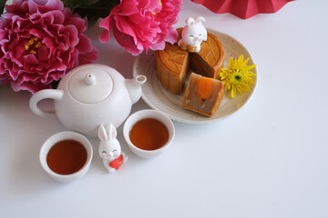 Top view of Chinese Mid-Autumn Festival concept made from mooncakes, tea decorated with plum blossom and rabbits isolated on white background.