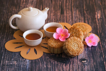 Chinese Mid-Autumn Festival concept made from mooncakes, tea decorated with plum blossom and rabbits on wooden background.