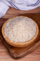 Fototapeta na wymiar Rice on wood background. Uncooked dry rice in wooden bowl
