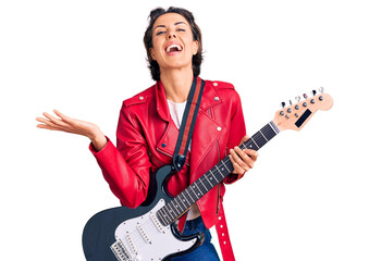 Young beautiful woman playing electric guitar celebrating victory with happy smile and winner...