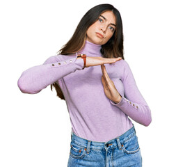 Young beautiful teen girl wearing turtleneck sweater doing time out gesture with hands, frustrated...