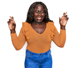 Young african woman wearing casual clothes gesturing finger crossed smiling with hope and eyes closed. luck and superstitious concept.