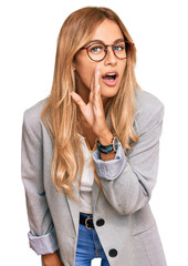 Beautiful blonde young woman wearing business clothes hand on mouth telling secret rumor,...
