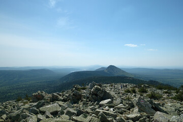 Panorama, landscape. In the foreground are rocks covered with moss, in the background are mountains. Summer, blue sky, day.