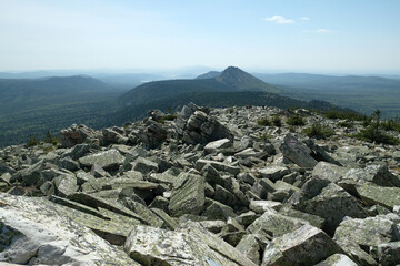 Panorama, landscape. In the foreground are rocks covered with moss, in the background are mountains. Summer, blue sky, day.