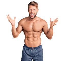 Fototapeta premium Young caucasian man standing shirtless celebrating crazy and amazed for success with arms raised and open eyes screaming excited. winner concept