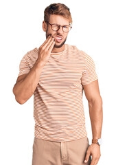 Young caucasian man wearing casual clothes and glasses touching mouth with hand with painful...