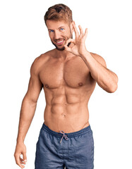 Young caucasian man standing shirtless smiling positive doing ok sign with hand and fingers. successful expression.