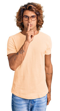Young hispanic man wearing casual clothes and glasses asking to be quiet with finger on lips. silence and secret concept.