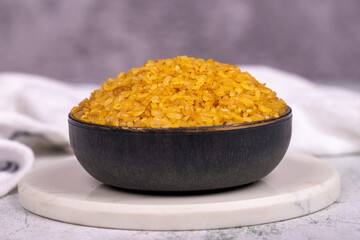 Bulgur on stone background. Bulgur wheat grains in bowl. Close up