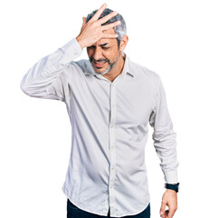 Middle age hispanic with grey hair wearing casual white shirt surprised with hand on head for mistake, remember error. forgot, bad memory concept.