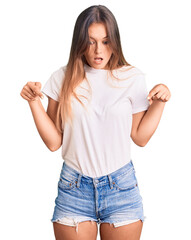 Beautiful caucasian woman wearing casual white tshirt pointing down with fingers showing advertisement, surprised face and open mouth