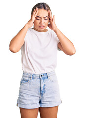 Fototapeta premium Young beautiful blonde woman wearing casual white tshirt with hand on head for pain in head because stress. suffering migraine.