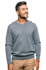 Handsome hispanic man wearing casual clothes looking away to side with smile on face, natural expression. laughing confident.