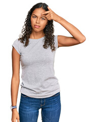 Young african american girl wearing casual clothes pointing unhappy to pimple on forehead, ugly infection of blackhead. acne and skin problem