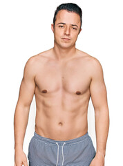 Fototapeta premium Handsome young man wearing swimwear shirtless looking sleepy and tired, exhausted for fatigue and hangover, lazy eyes in the morning.