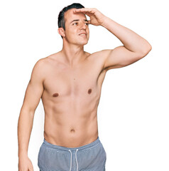 Fototapeta premium Handsome young man wearing swimwear shirtless smiling confident touching hair with hand up gesture, posing attractive and fashionable