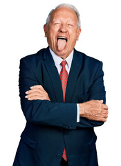 Senior business man with grey hair with arms crossed gesture sticking tongue out happy with funny expression.