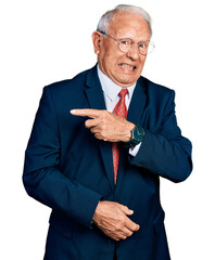 Senior man with grey hair wearing business suit and glasses pointing aside worried and nervous with forefinger, concerned and surprised expression