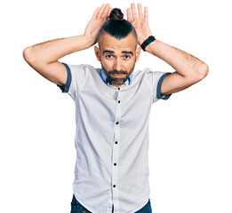 Fototapeta premium Hispanic man with ponytail wearing casual white shirt doing bunny ears gesture with hands palms looking cynical and skeptical. easter rabbit concept.