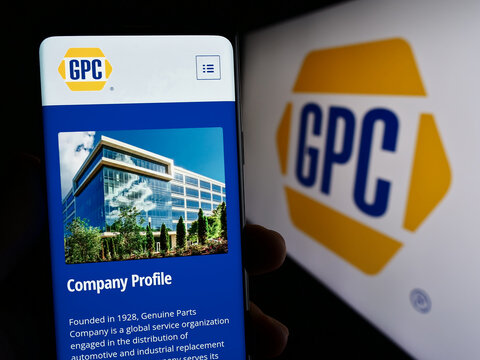 Stuttgart, Germany - 07-01-2023: Person holding mobile phone with webpage of US business Genuine Parts Company (GPC) on screen in front of logo. Focus on center of phone display.