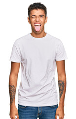 Obraz premium Young handsome african american man wearing casual white tshirt sticking tongue out happy with funny expression. emotion concept.