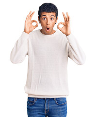 Young african amercian man wearing casual clothes looking surprised and shocked doing ok approval symbol with fingers. crazy expression