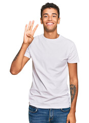 Fototapeta premium Young handsome african american man wearing casual white tshirt showing and pointing up with fingers number four while smiling confident and happy.