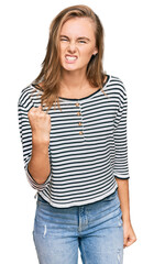 Obraz premium Beautiful blonde woman wearing casual clothes angry and mad raising fist frustrated and furious while shouting with anger. rage and aggressive concept.