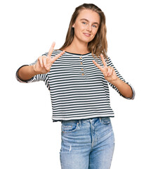 Beautiful blonde woman wearing casual clothes smiling looking to the camera showing fingers doing victory sign. number two.