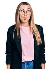 Hispanic young woman wearing business jacket and glasses making fish face with lips, crazy and comical gesture. funny expression.