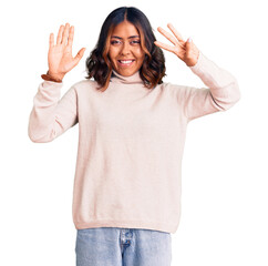 Young beautiful mixed race woman wearing winter turtleneck sweater showing and pointing up with fingers number eight while smiling confident and happy.