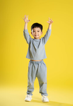full body image of boy posing on a yellow background.