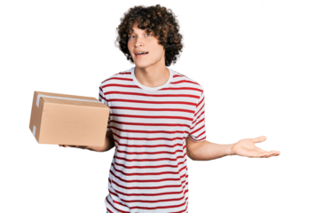 Caucasian teenager holding delivery package celebrating achievement with happy smile and winner expression with raised hand