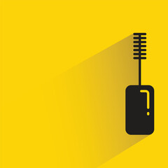 mascara with shadow on yellow background