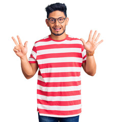 Handsome latin american young man wearing casual clothes and glasses showing and pointing up with fingers number eight while smiling confident and happy.