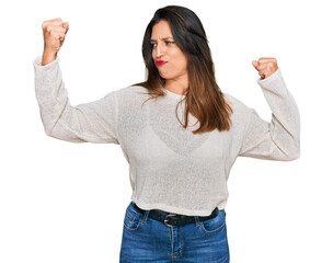 Beautiful hispanic woman wearing casual sweater showing arms muscles smiling proud. fitness concept.