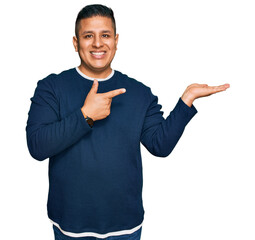 Young latin man wearing casual clothes amazed and smiling to the camera while presenting with hand...