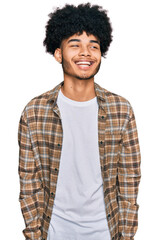 Young african american man with afro hair wearing casual clothes looking away to side with smile on...