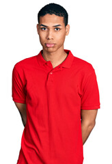 Fototapeta premium Young hispanic man wearing casual red t shirt depressed and worry for distress, crying angry and afraid. sad expression.