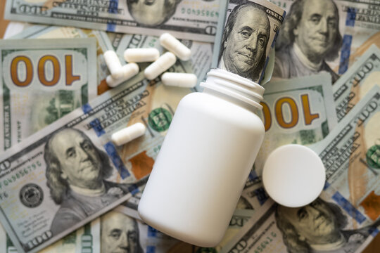 White jar with pills close-up on the background of dollars.