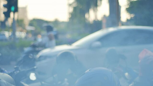 ars moving through thick smoke and motorcycles parked in urban Jakarta. It depicts high pollution, heat, congestion, fatigue from work, and boredom.