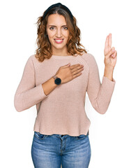 Beautiful young caucasian woman wearing casual sweater smiling swearing with hand on chest and...