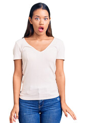 Obraz premium Young beautiful latin girl wearing casual white t shirt scared and amazed with open mouth for surprise, disbelief face
